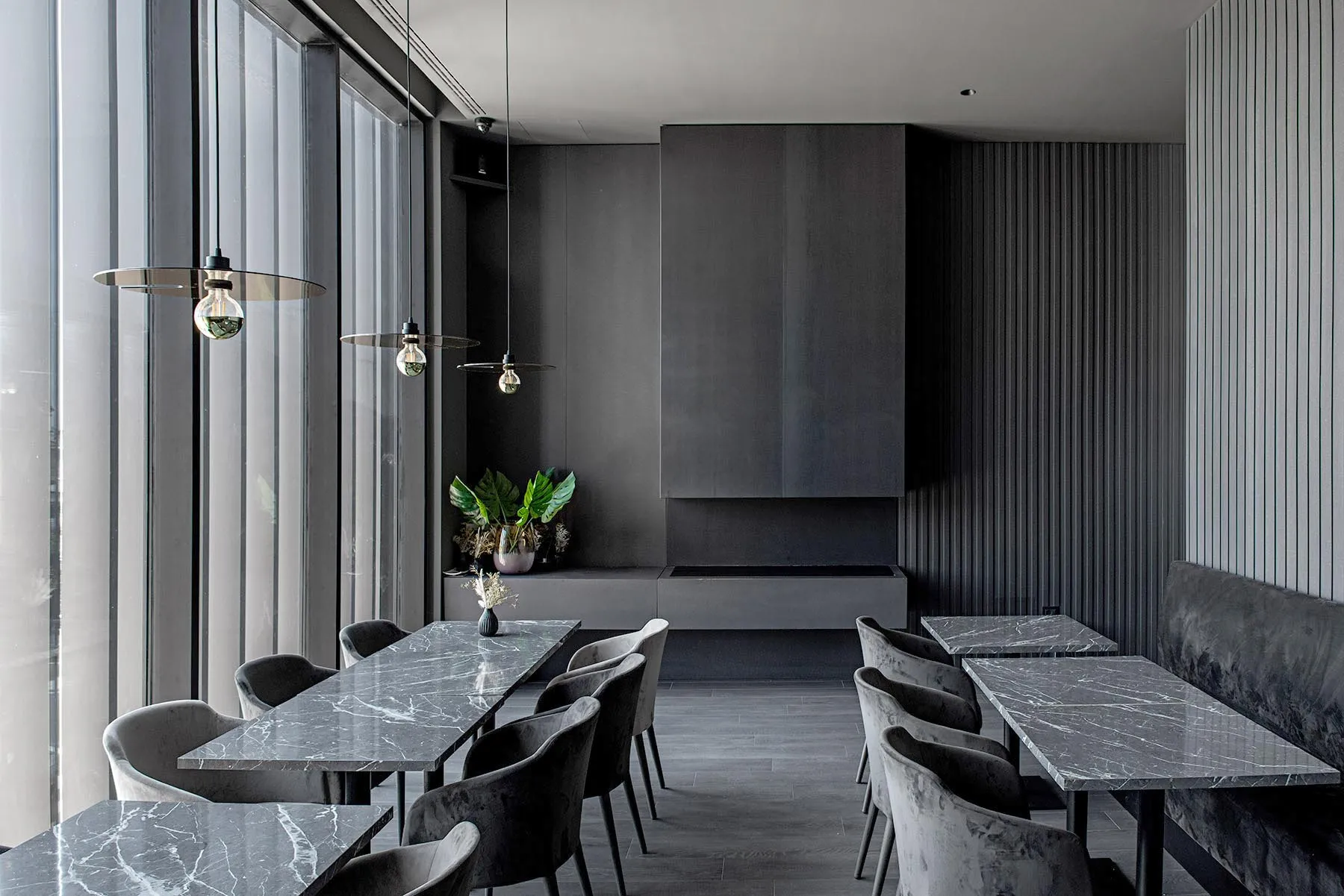 A modern restaurant with sleek marble tables and chairs, featuring industrial-style lighting and minimalist design.