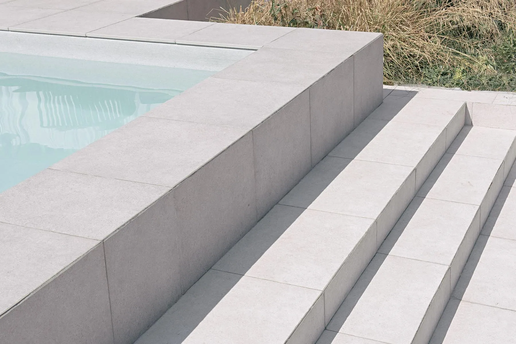 Concrete stairs leading into a modern swimming pool.