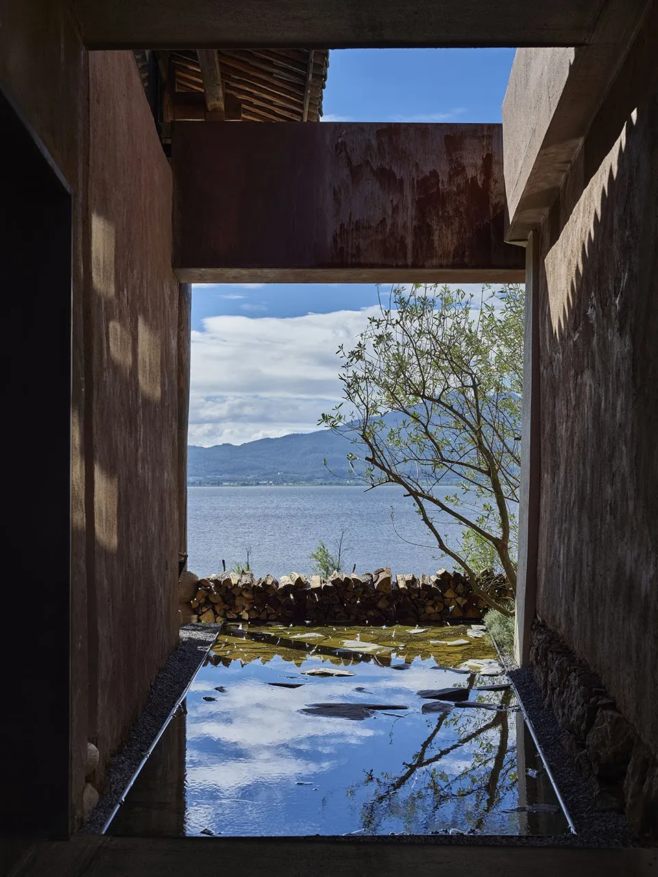Concrete pool and patio overlooking a serene waterfront landscape