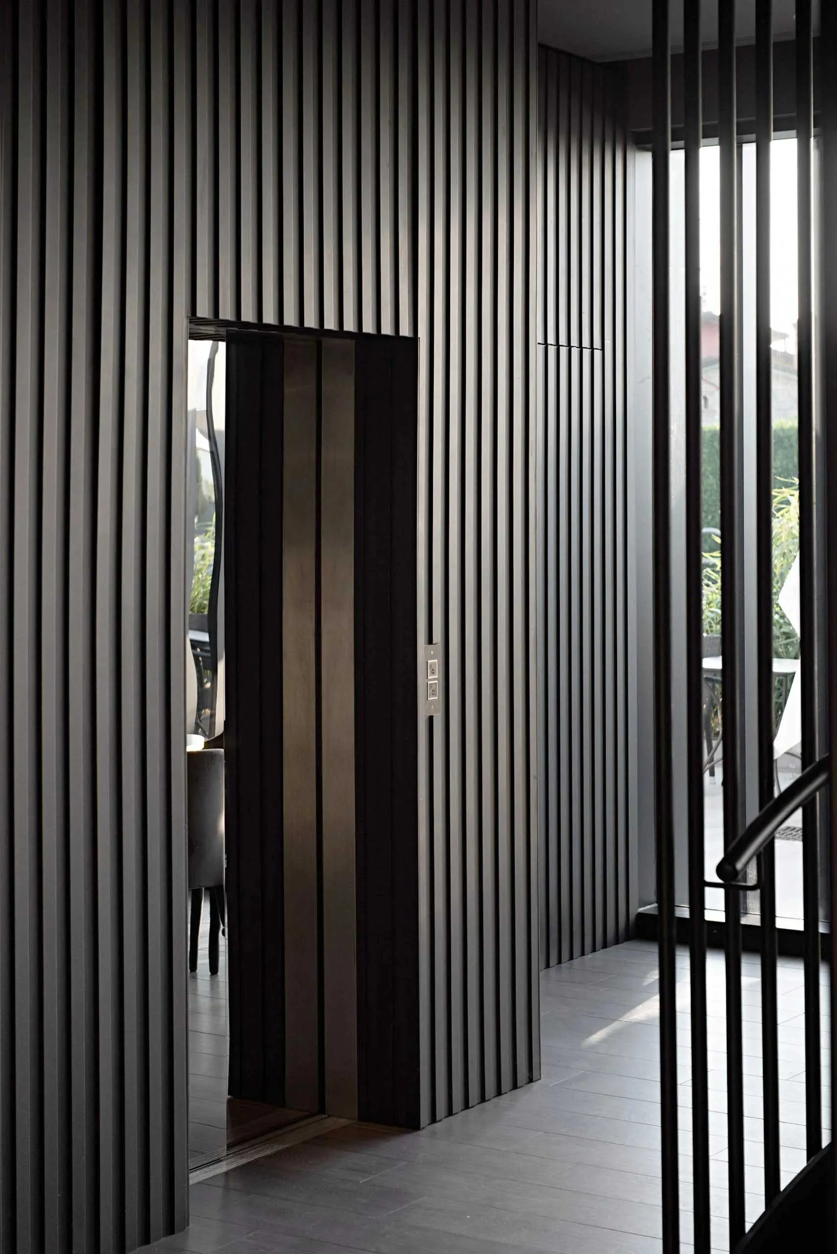 A modern elevator interior with metallic panels and a glass door.