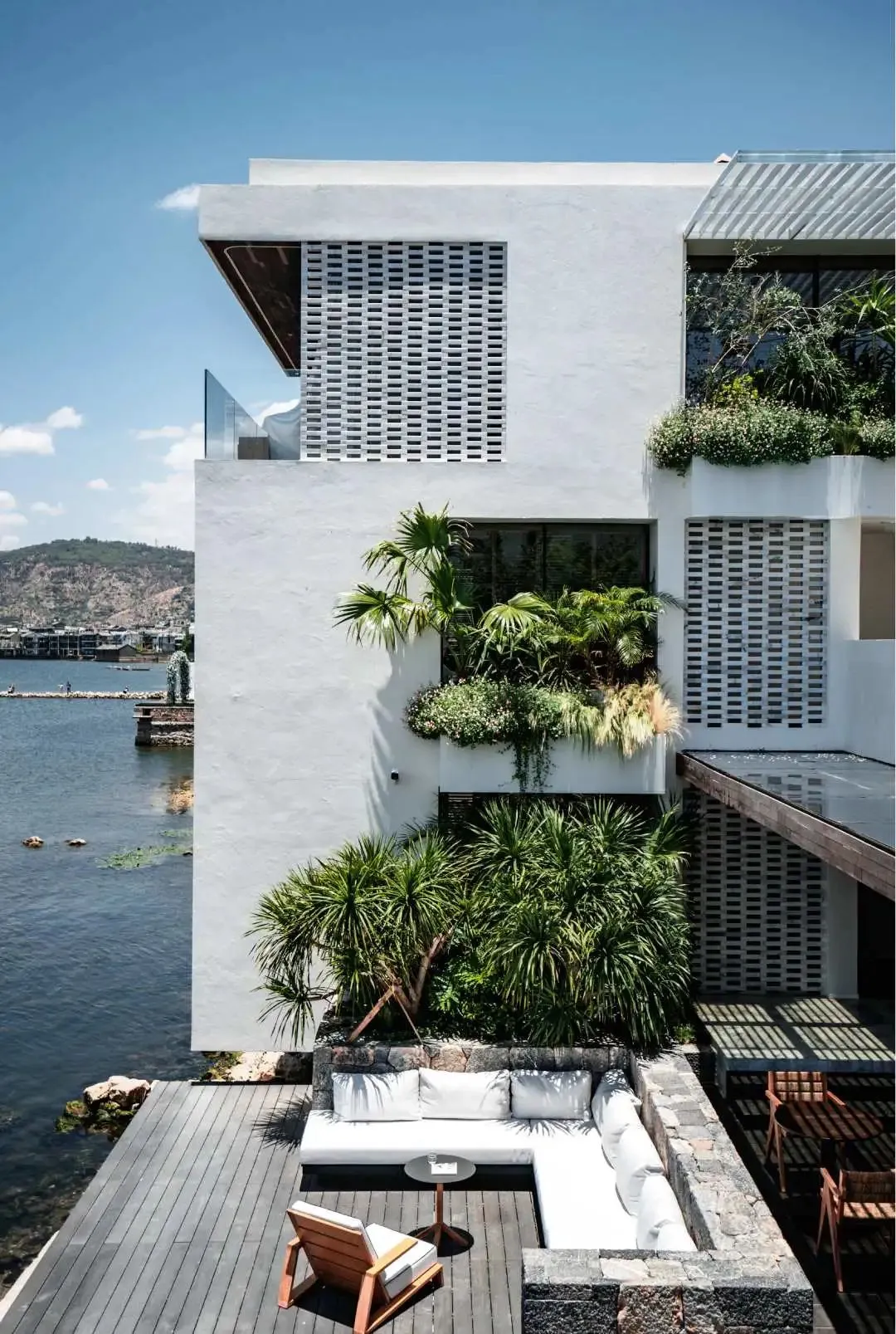 Modern residential exterior with minimalist design, featuring concrete and glass elements, surrounded by water.