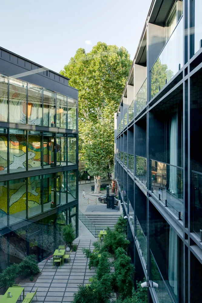 Outdoor courtyard with modern glass buildings and greenery.