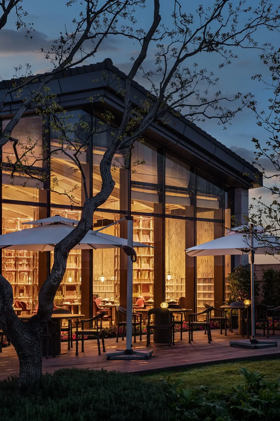 Modern restaurant exterior with glass walls at dusk