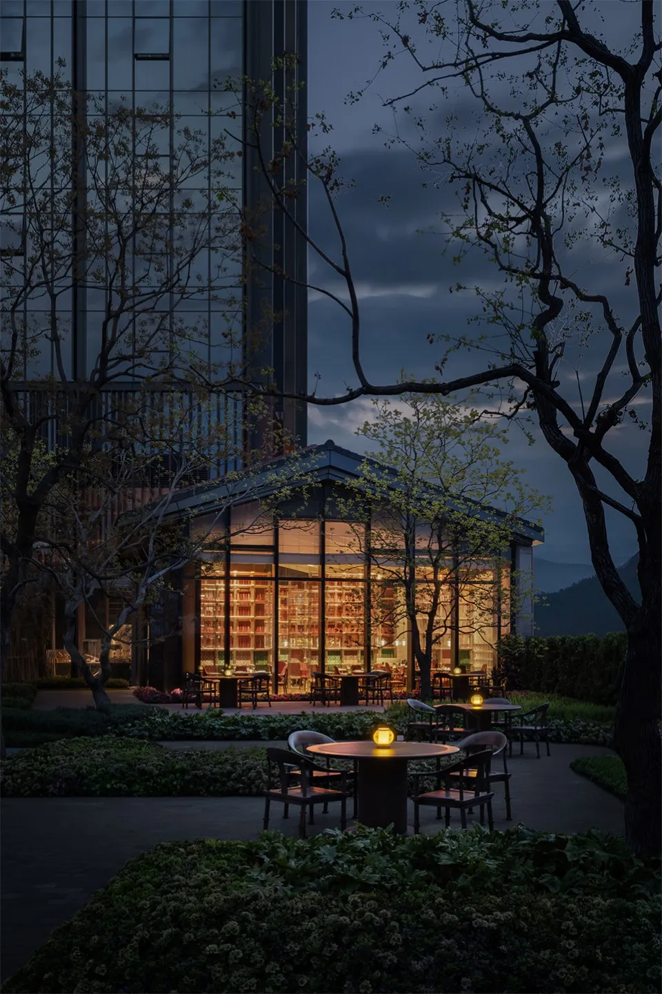 A modern restaurant with glass walls, concrete floors, and warm lighting.