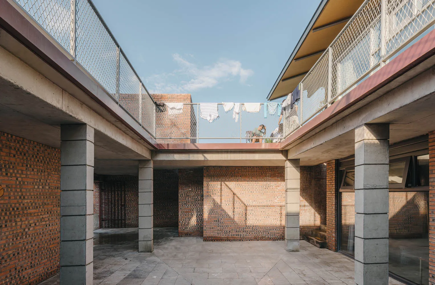 An image of a residential patio made of red brick and concrete, with laundry hanging on a clothesline in the background.