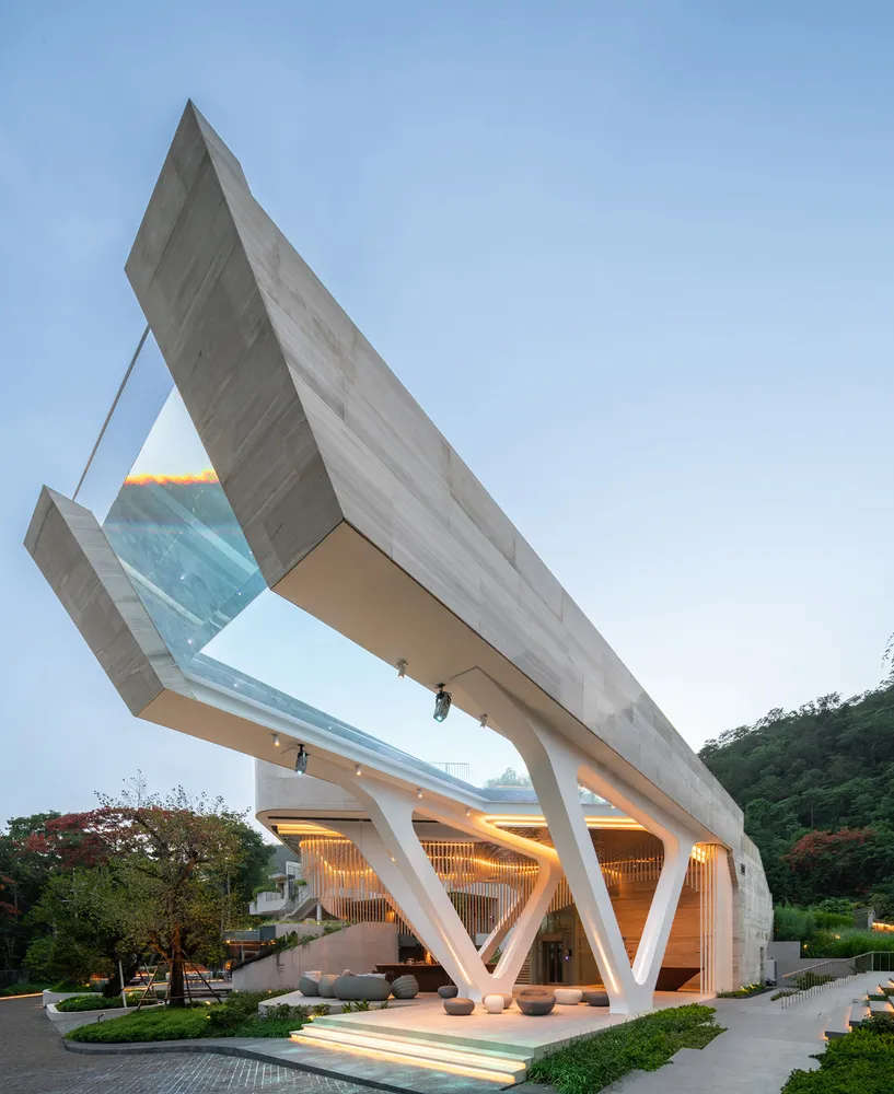 A modern building with a concrete and glass exterior, featuring an angular, open design.
