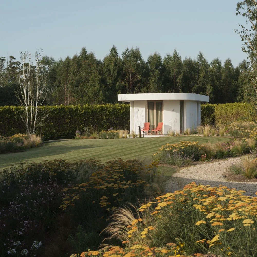 A modern garden featuring gravel pathways, flowerbeds filled with colorful flowers, and neatly trimmed hedges.