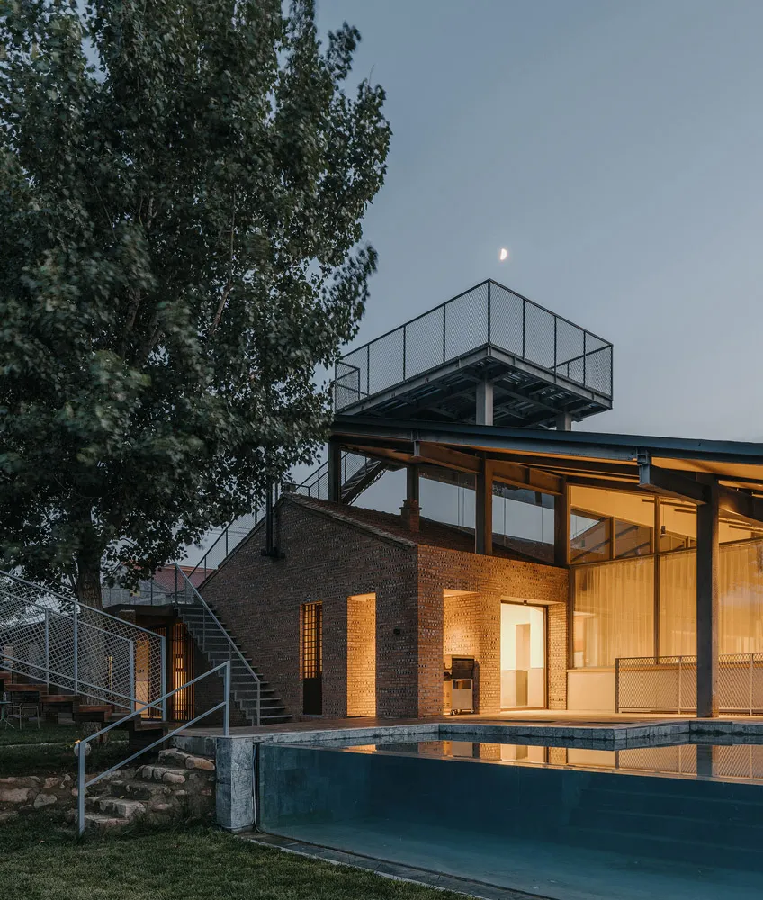 Modern house exterior with brick walls and glass windows at dusk.