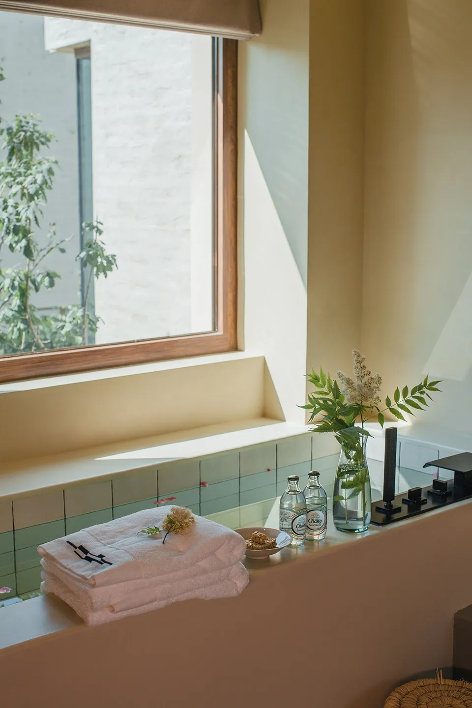 A minimalist bathroom featuring stone tiles and a window with greenery outside.