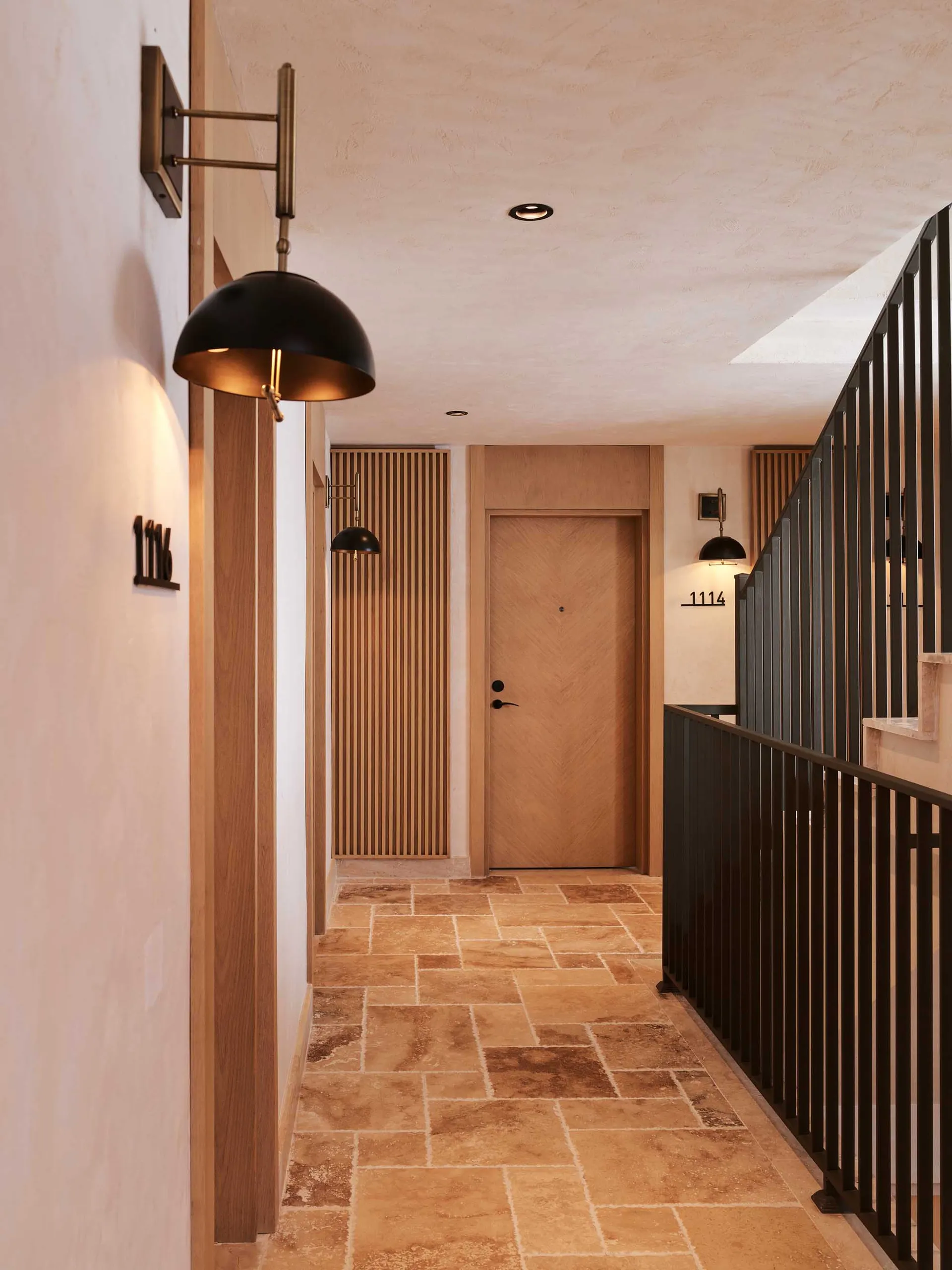 A modern corridor with stone flooring and wooden doors.