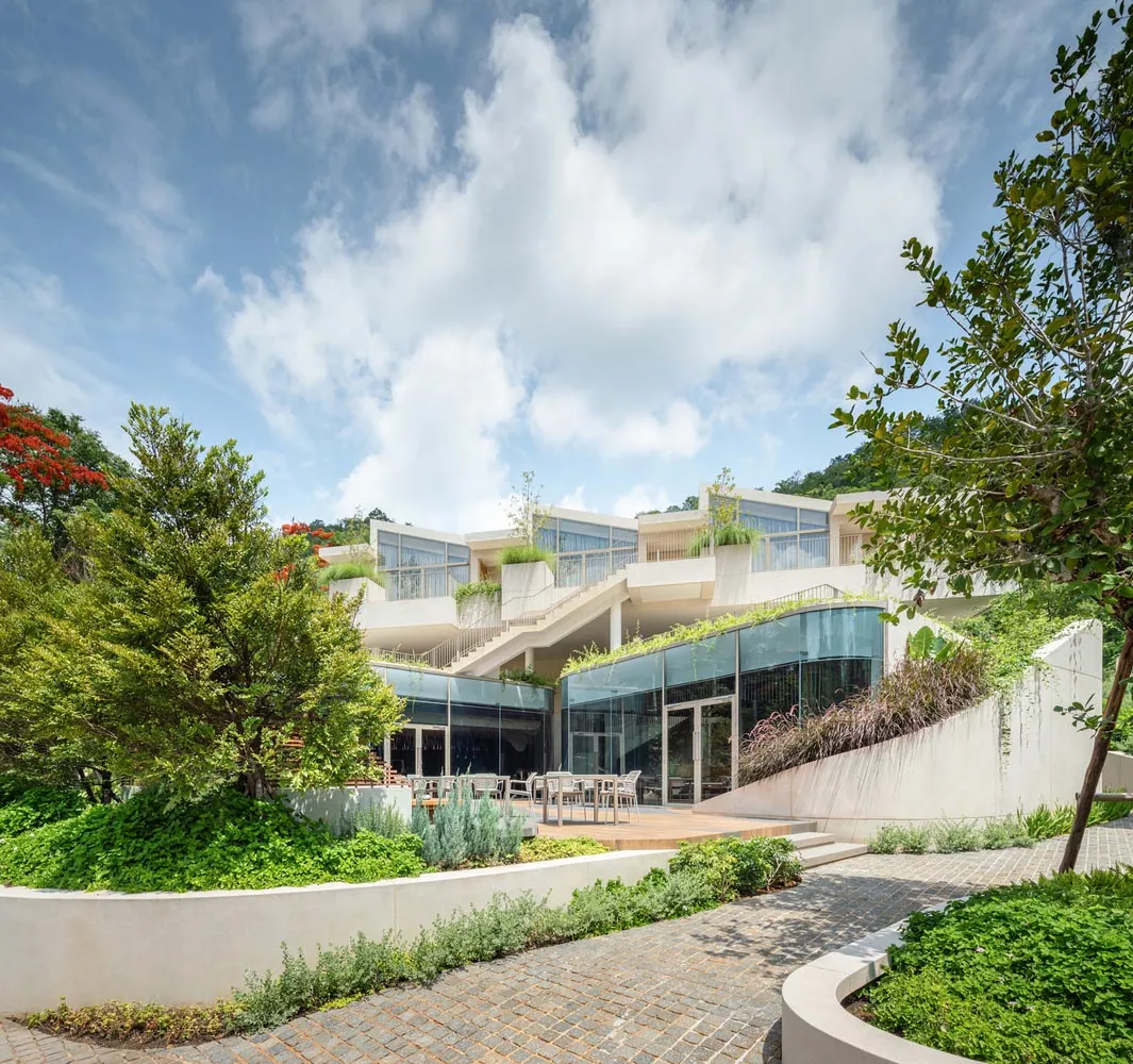 現代住宅建築採用白色混凝土外觀，搭配大面窗與綠意植栽。
