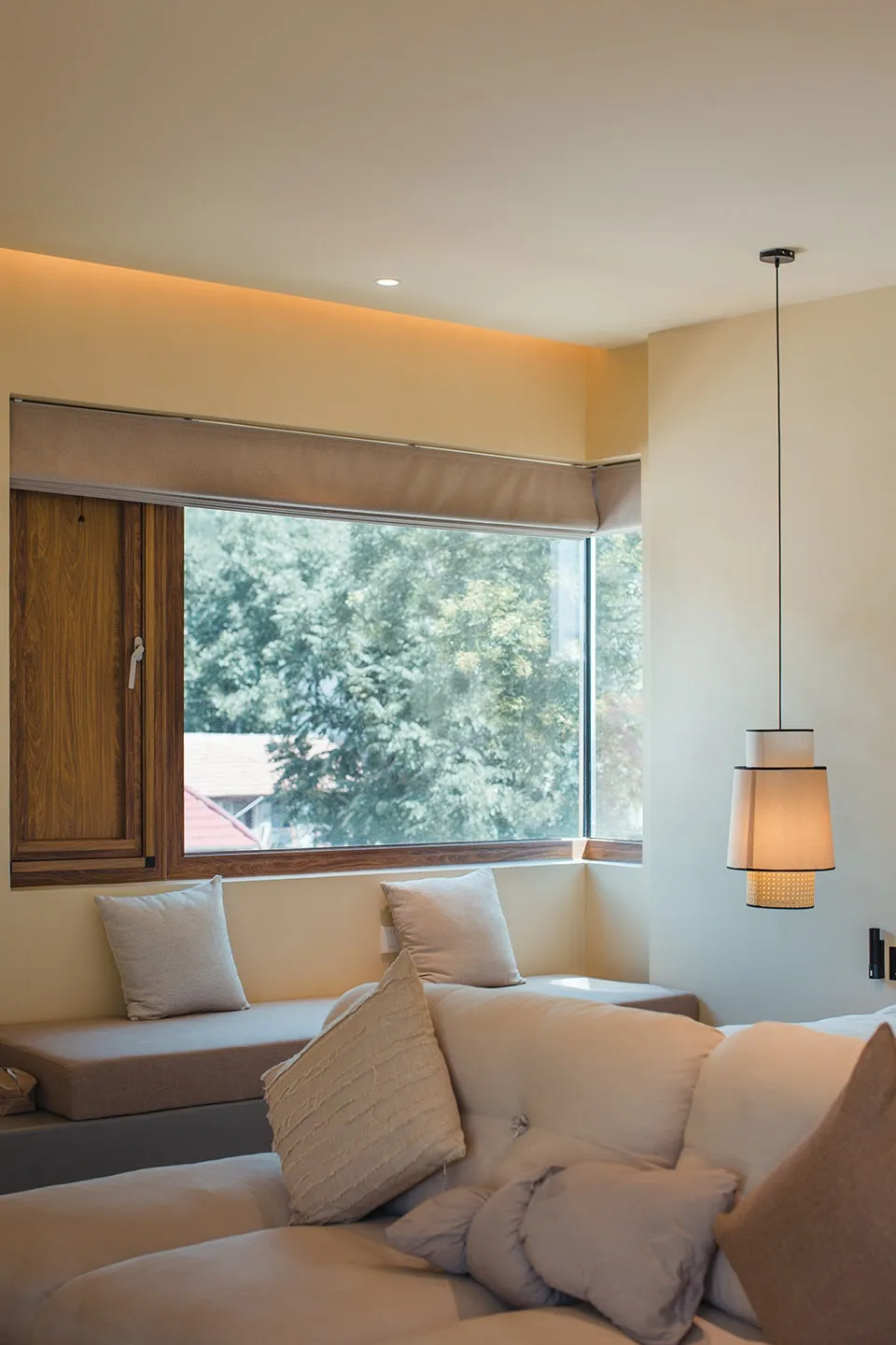 A minimalist living room with beige furniture and a large window.
