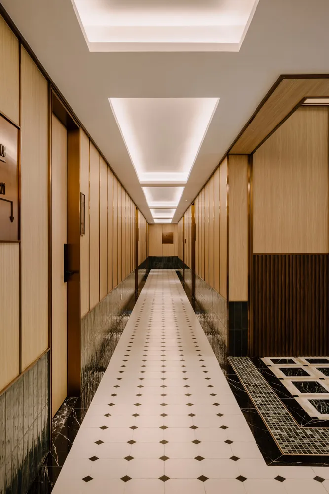 Modern hotel hallway featuring marble walls and a wooden floor.