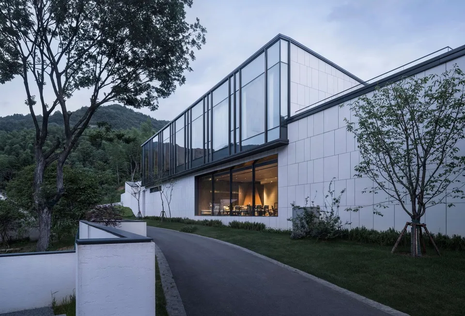 A modern residential building with glass walls and white tiled exteriors.