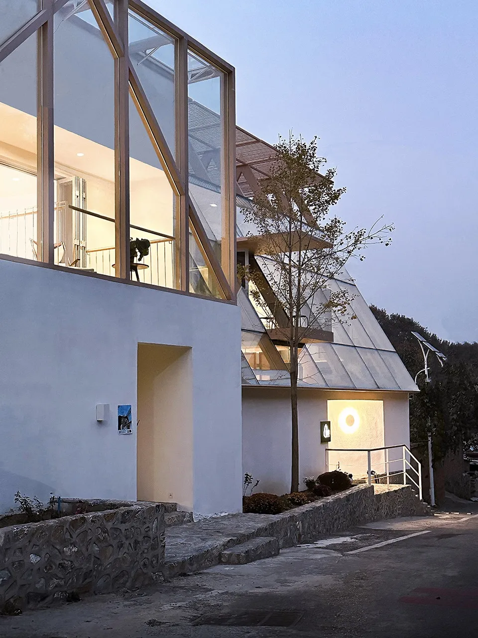 Modern residential exterior featuring large glass windows, wooden accents, and metallic roof.