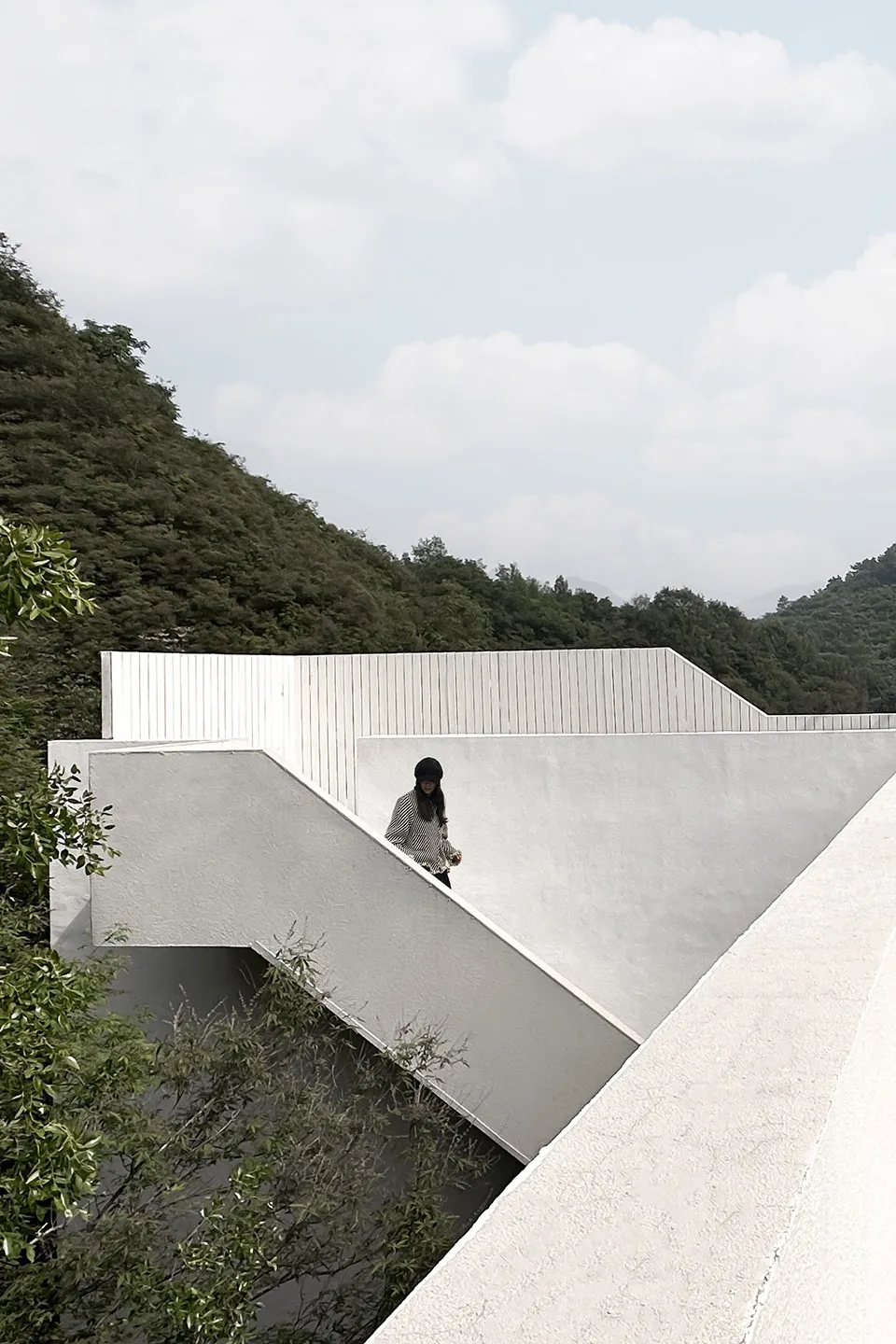 A person climbing a modern white staircase in a natural landscape.