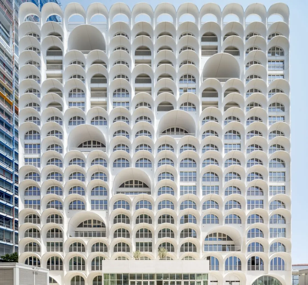 Modern building facade with repeating concrete arches and glass windows.