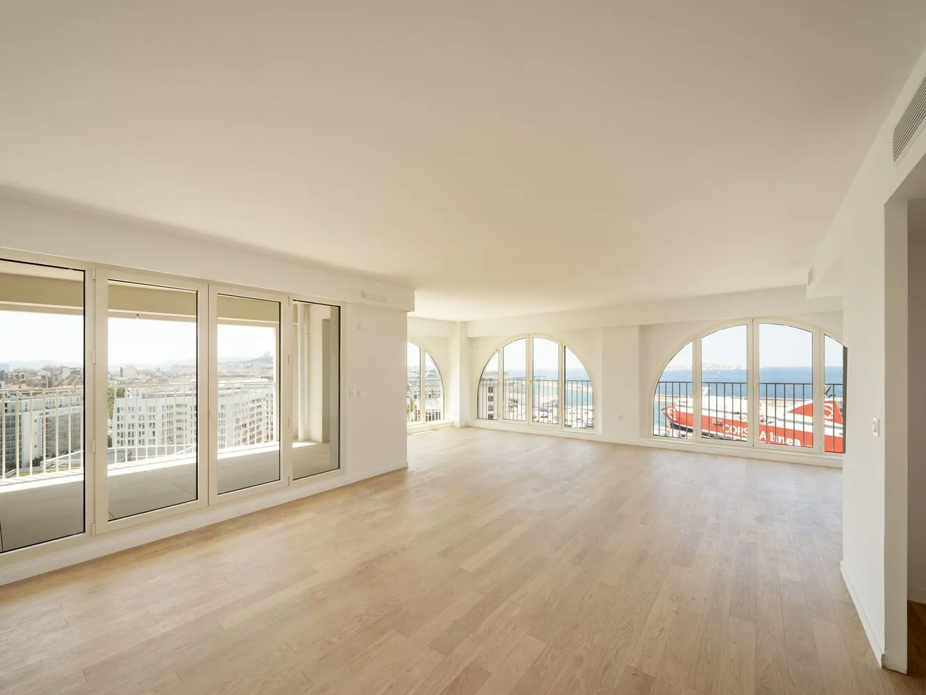 Modern apartment living room featuring hardwood flooring and large glass windows.