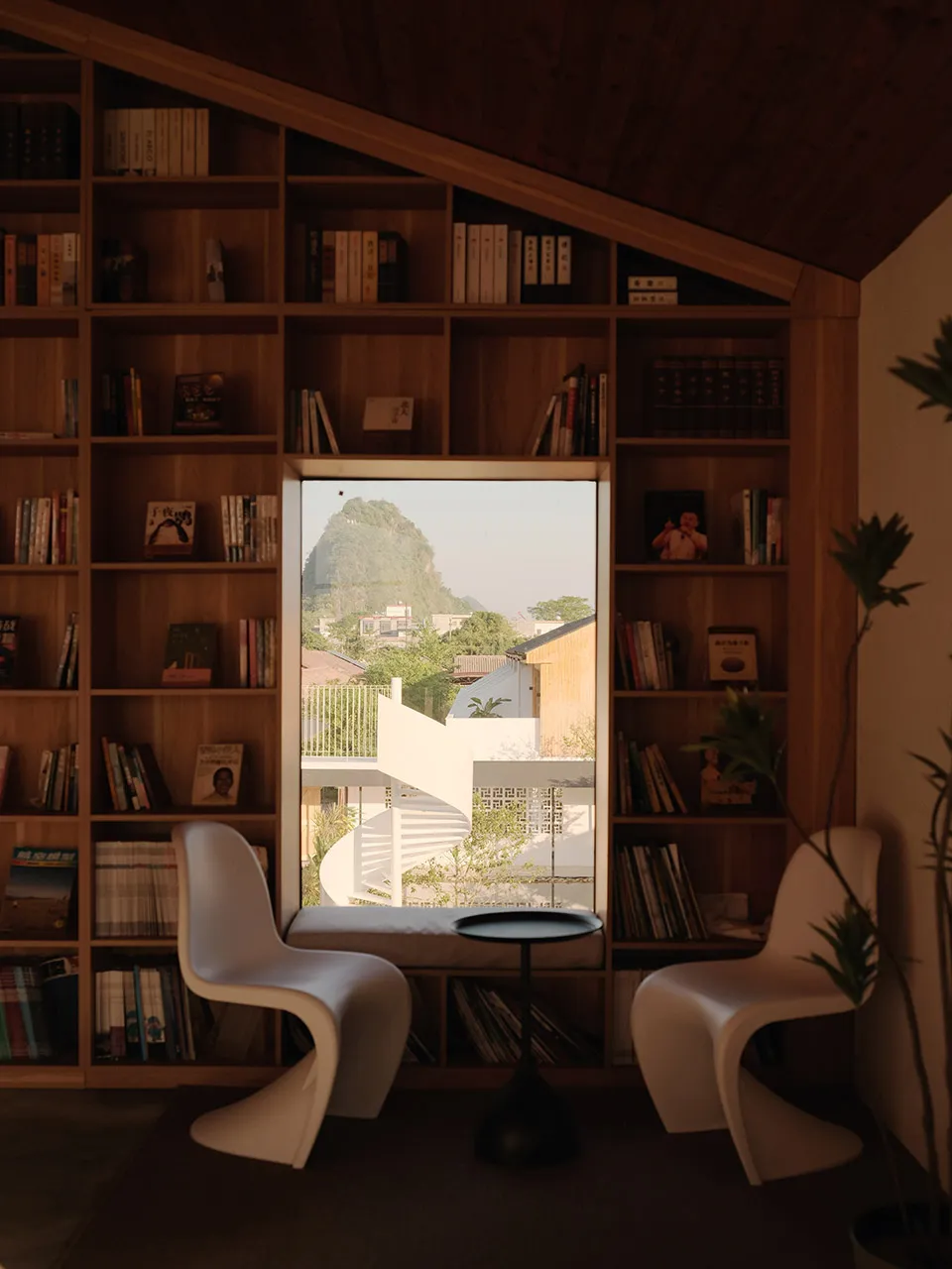 A cozy indoor library with wooden shelves and concrete floor, featuring a wooden bench and bookshelves filled with books, loo