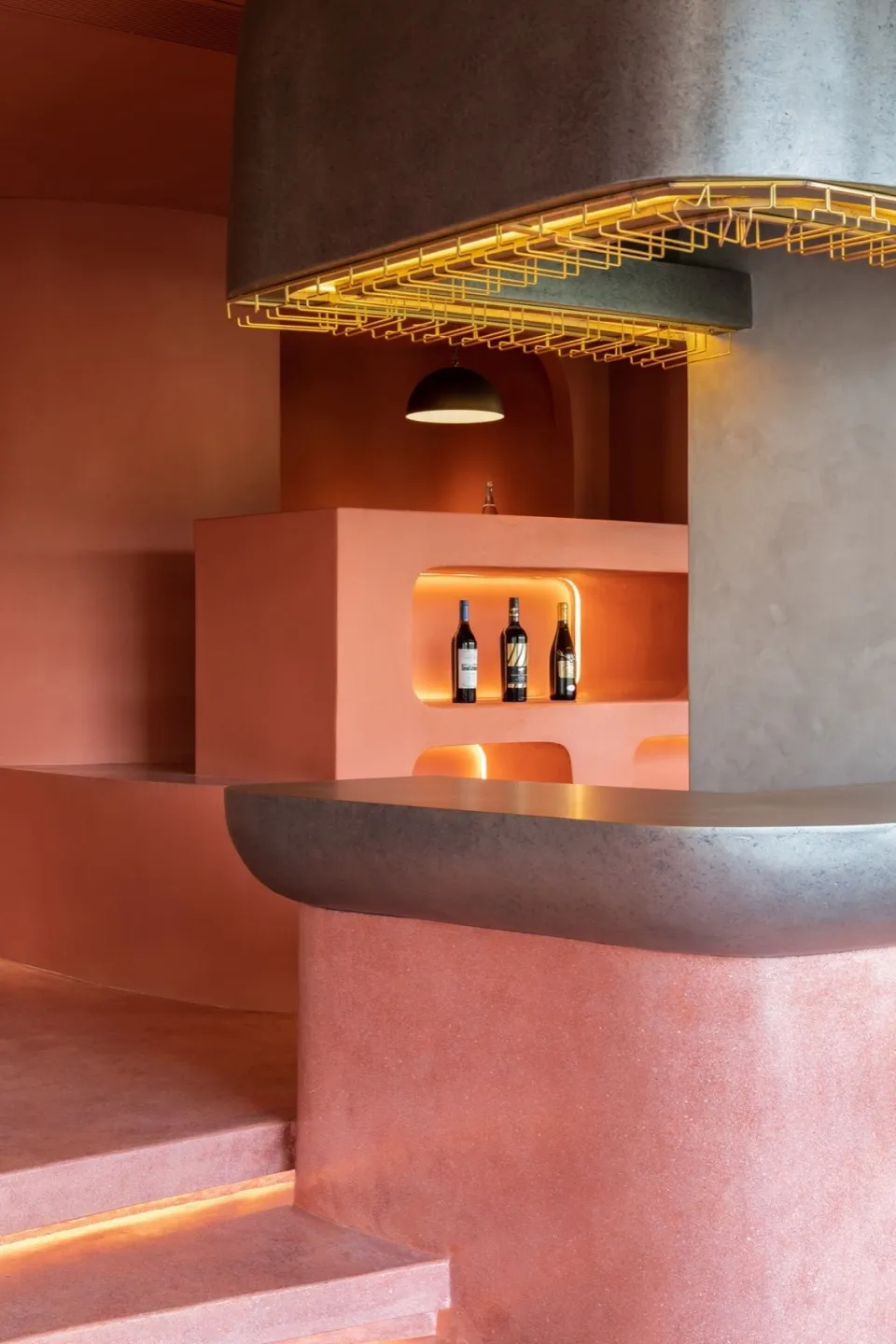 Minimalist restaurant bar with concrete walls and a curved bar counter.