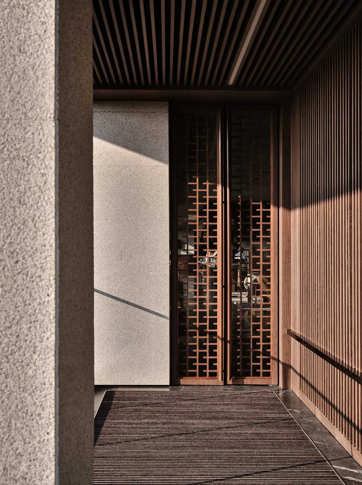 A modern wooden lattice entrance with a stone wall.