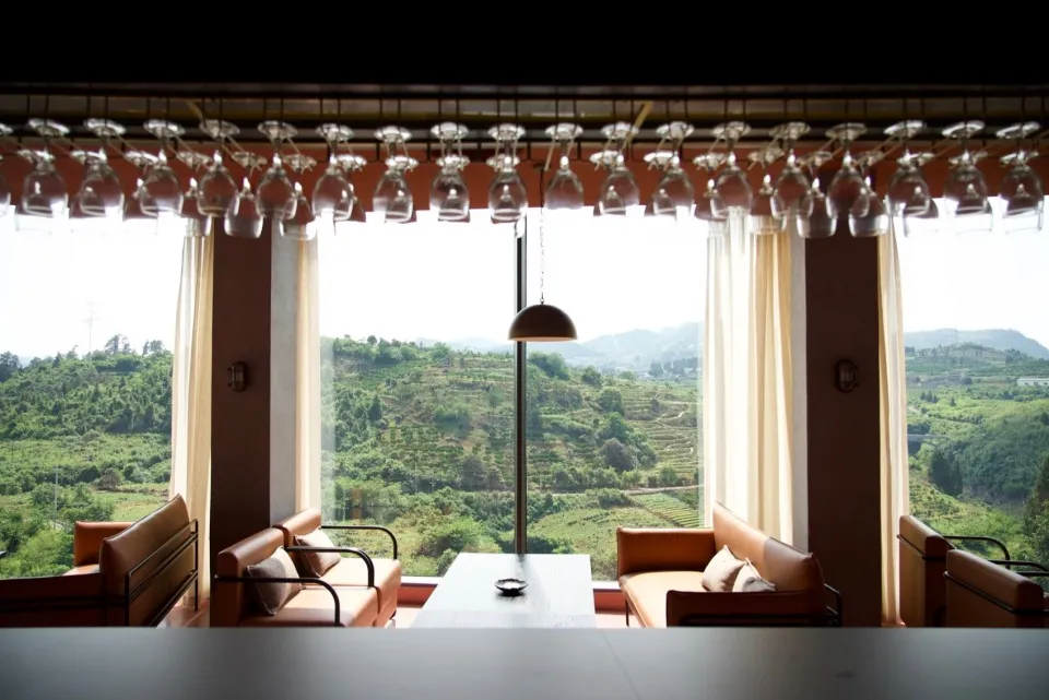 A modern restaurant interior with a glass ceiling overlooking lush green hills.