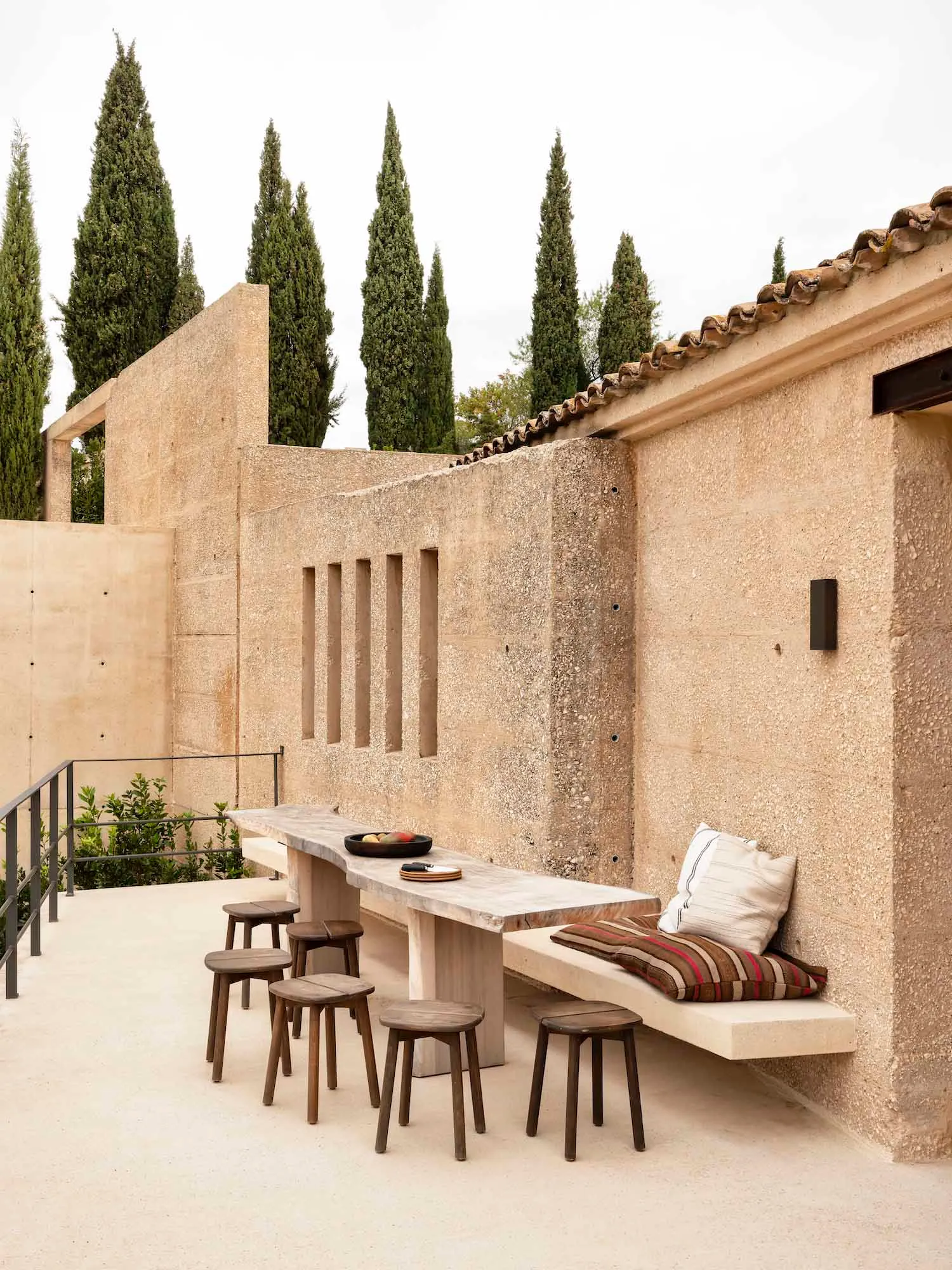 A minimalist outdoor seating area with concrete furniture and stools.