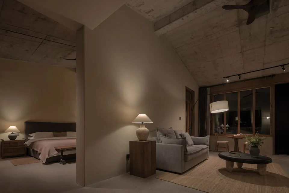 Modern industrial residential interior with concrete walls and ceiling, featuring a cozy living area with a couch and floor l
