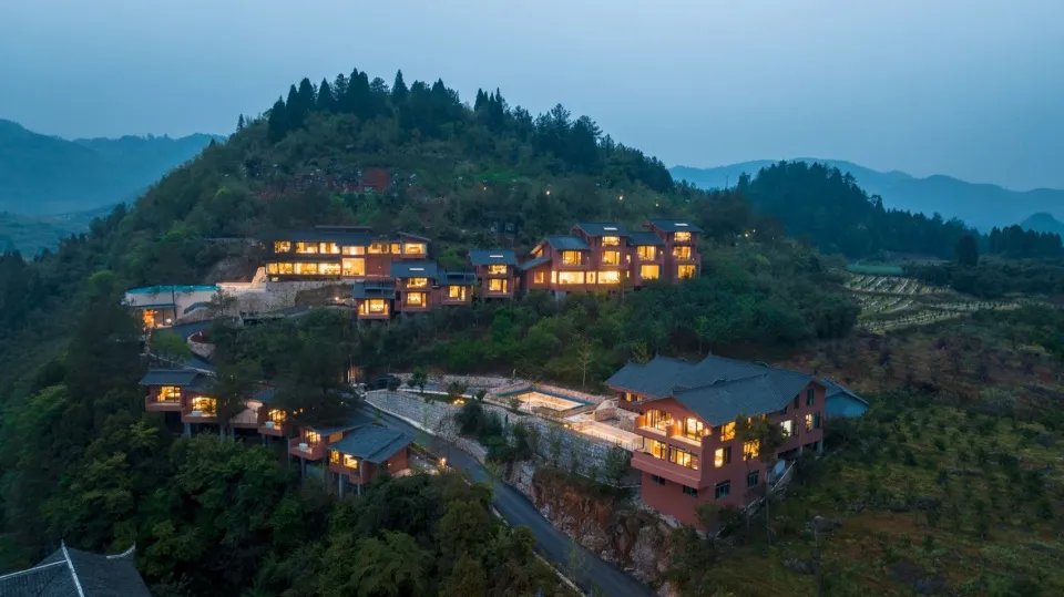 現代住宅建築群燈火通明，坐落於山坡上。
