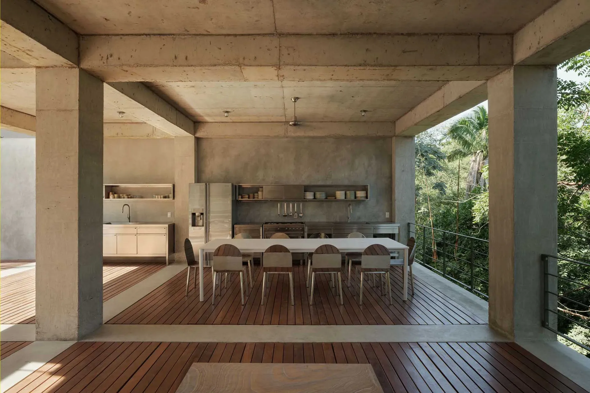 Modern dining room with concrete exterior and steel and wooden furniture.