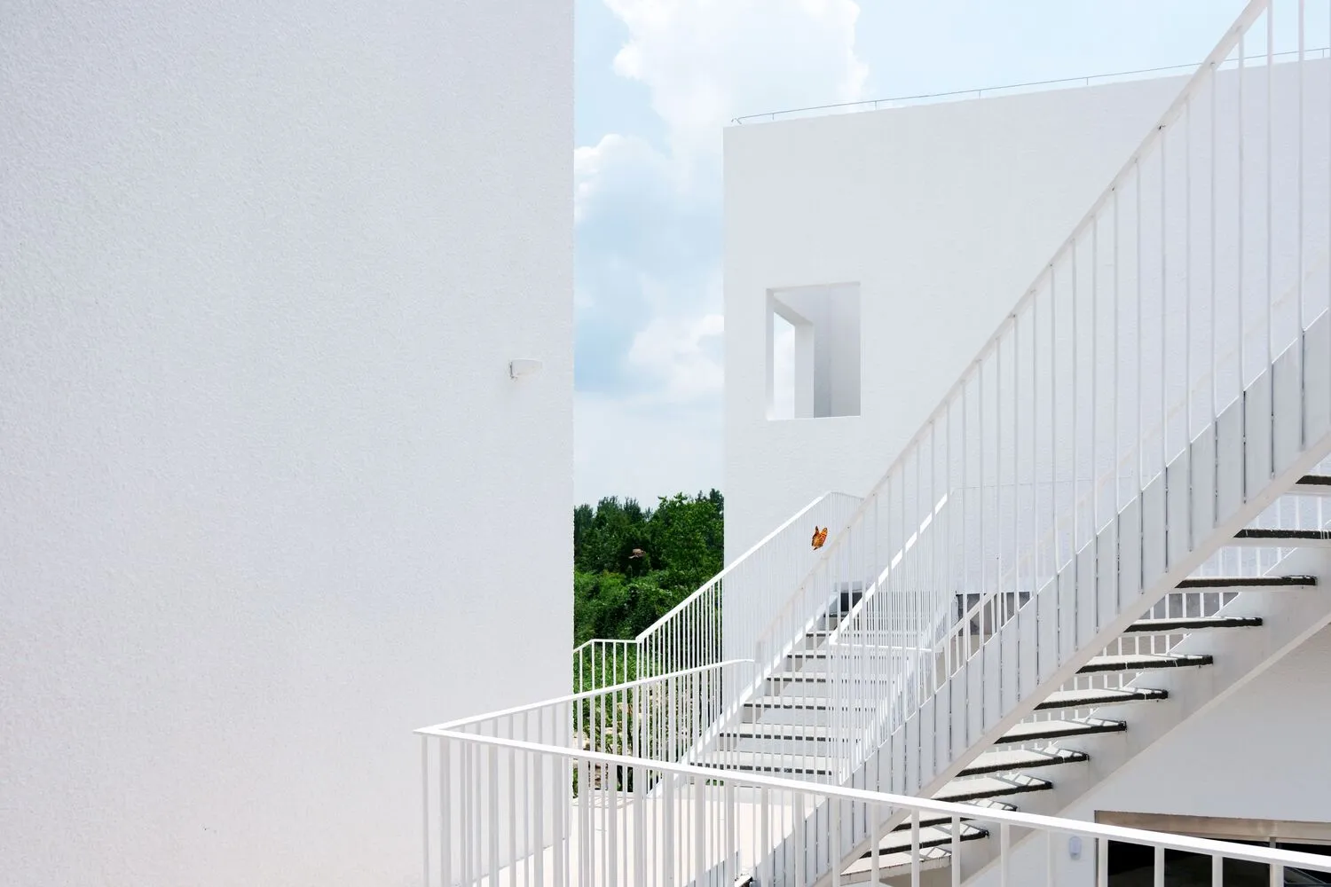 White metal staircase with railings and a view of greenery in the background.