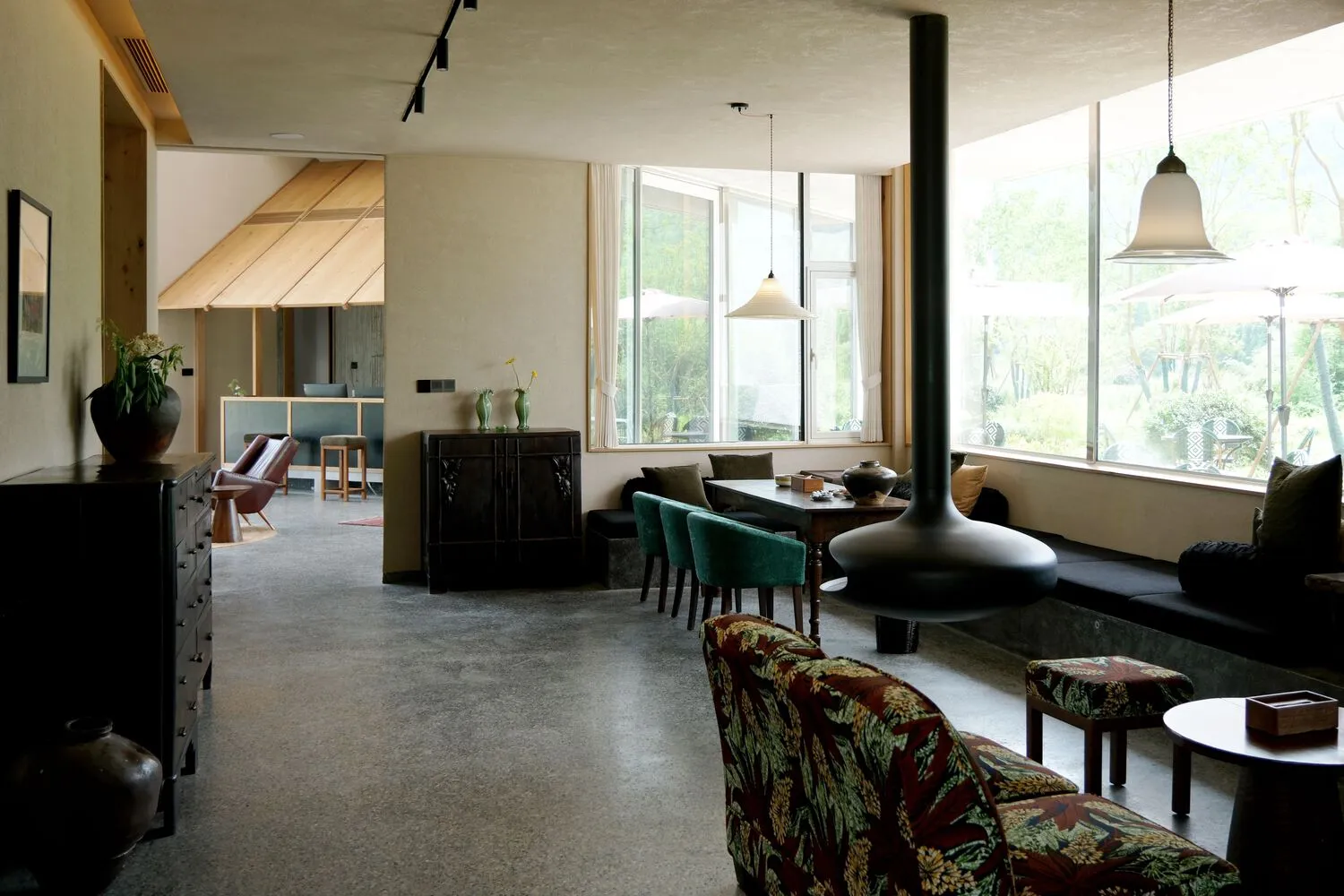 A minimalist living room with concrete floors, modern furniture, and large windows.
