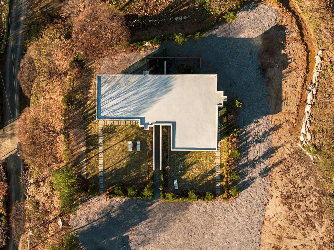 A modern house with a minimalist architectural design, featuring concrete surfaces and a flat roof.