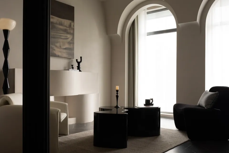 A modern living room with minimalist furniture, white walls, and large windows.