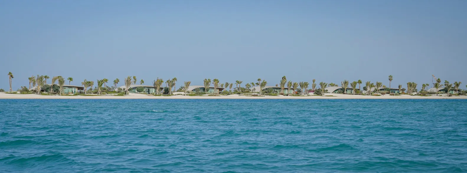 A serene beachfront view showcasing residential houses amidst sandy terrain and water.