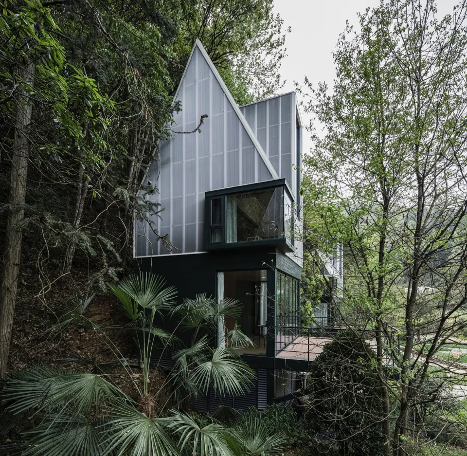 Modern residential house with metal exterior surrounded by trees and greenery.