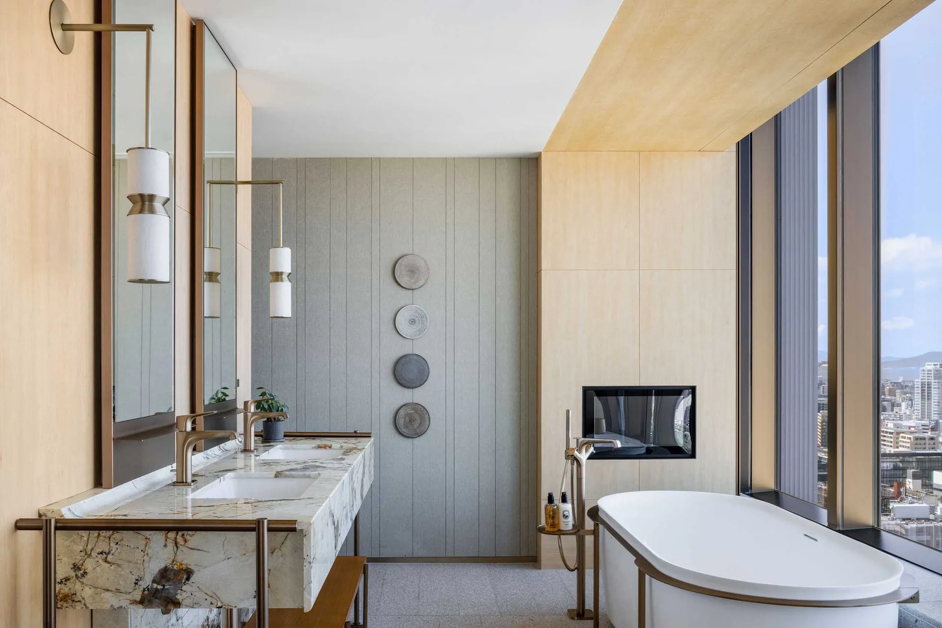 Modern bathroom featuring marble and metal materials with a sleek freestanding bathtub, floating vanity, and large windows.