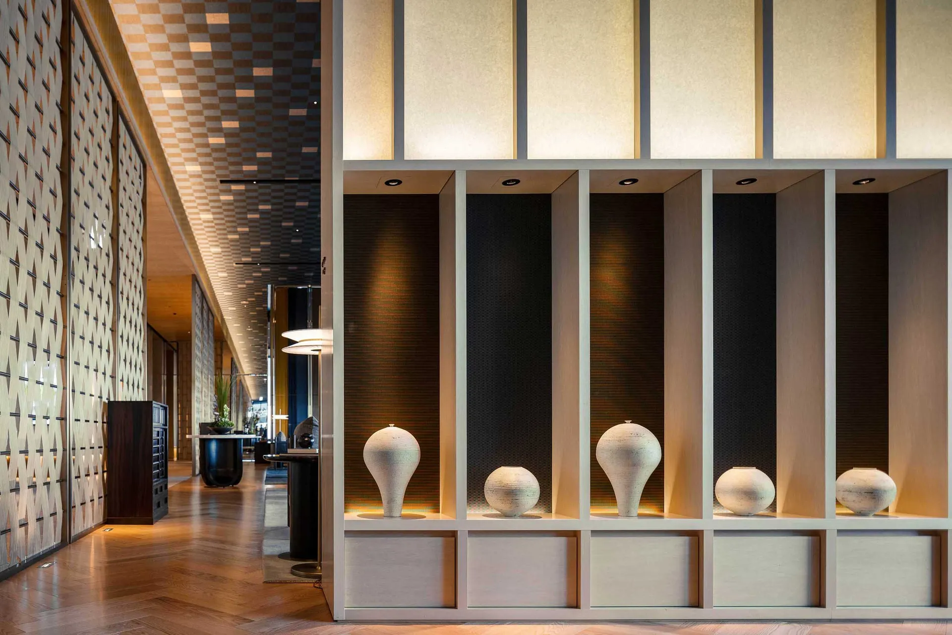 Modern hotel corridor featuring concrete and wooden flooring with illuminated lighting.