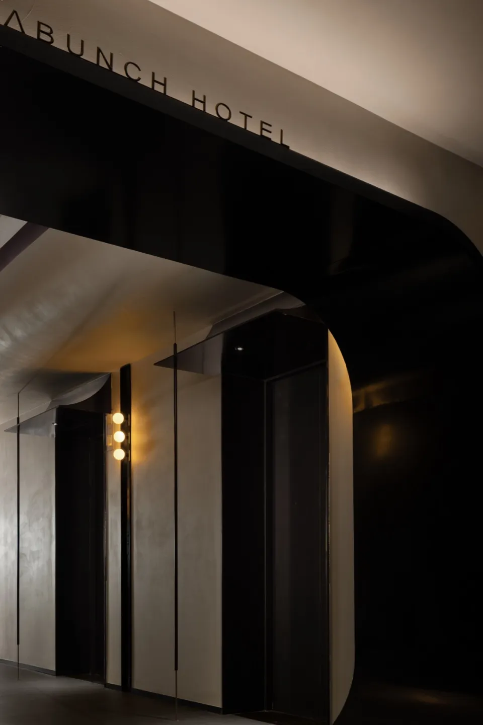 Modern, black and white hotel entrance with metallic accents and concrete walls