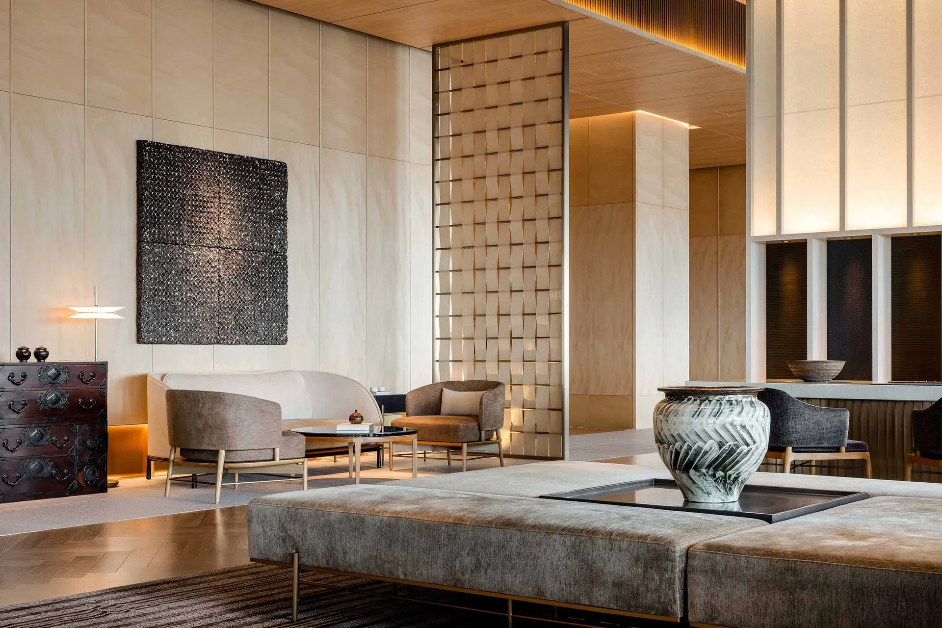 A modern living room featuring beige upholstered furniture, wooden paneling, and metallic accents.