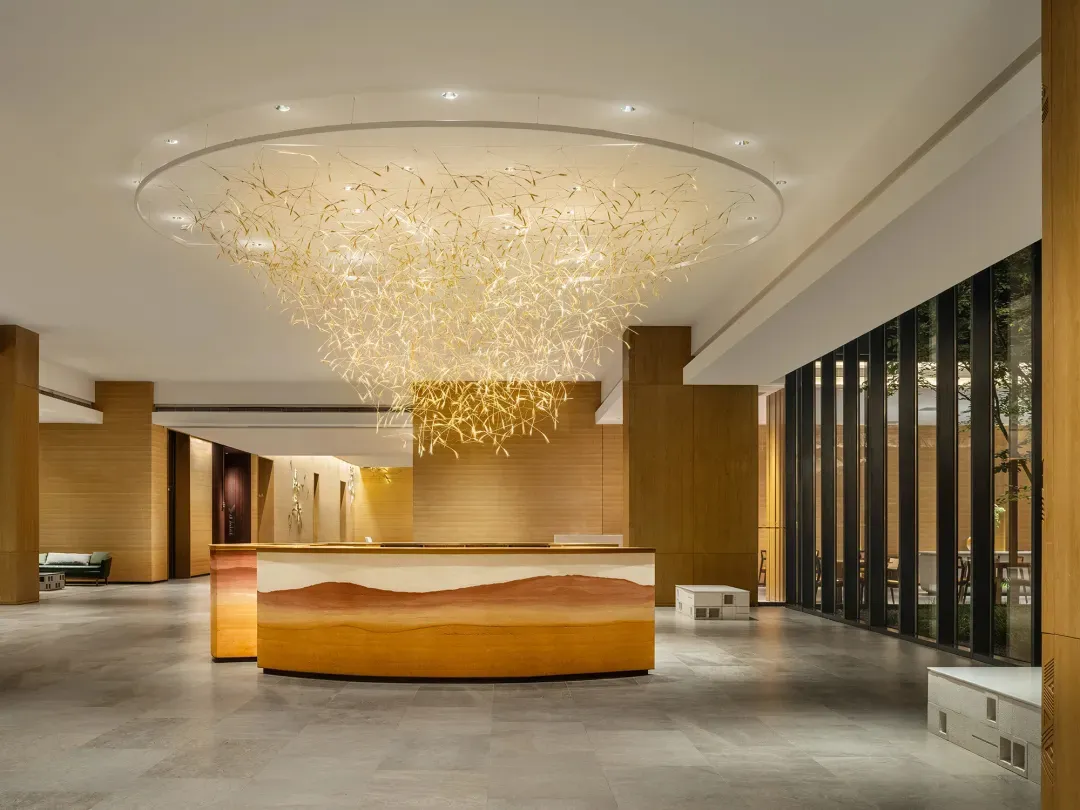 A modern lobby featuring a metallic lighting fixture and wooden reception desk.