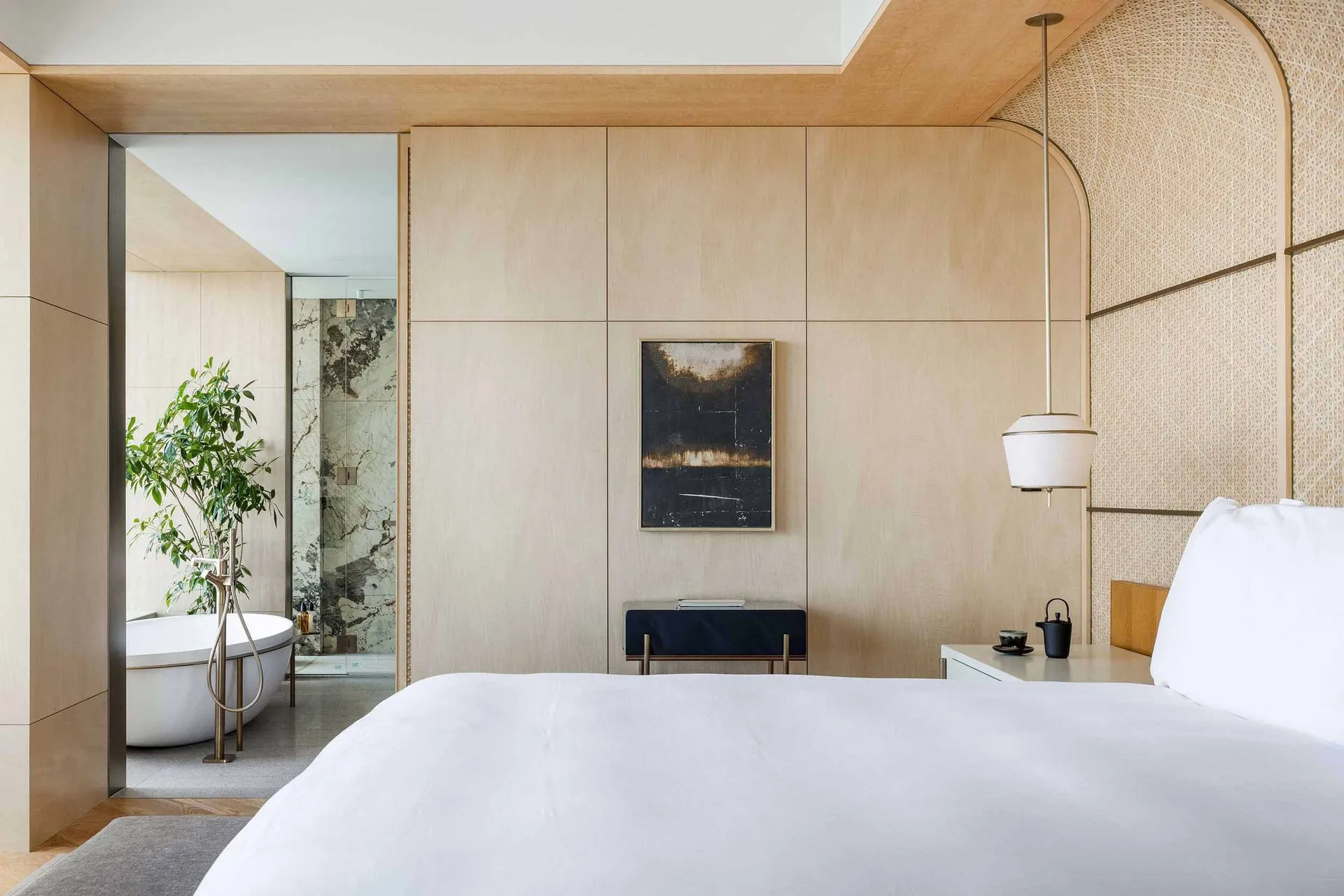 A contemporary bedroom with a king-sized bed, minimalist decor, and luxurious materials like wood, marble, and fabric.