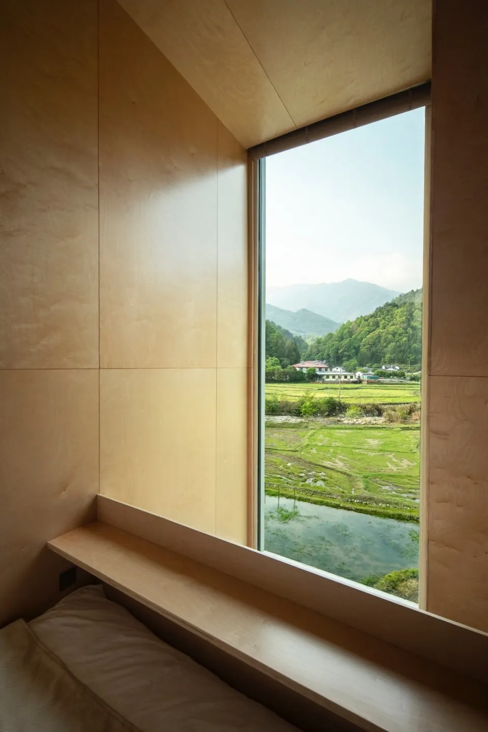 Wood-paneled wall with a window overlooking a lush green landscape.