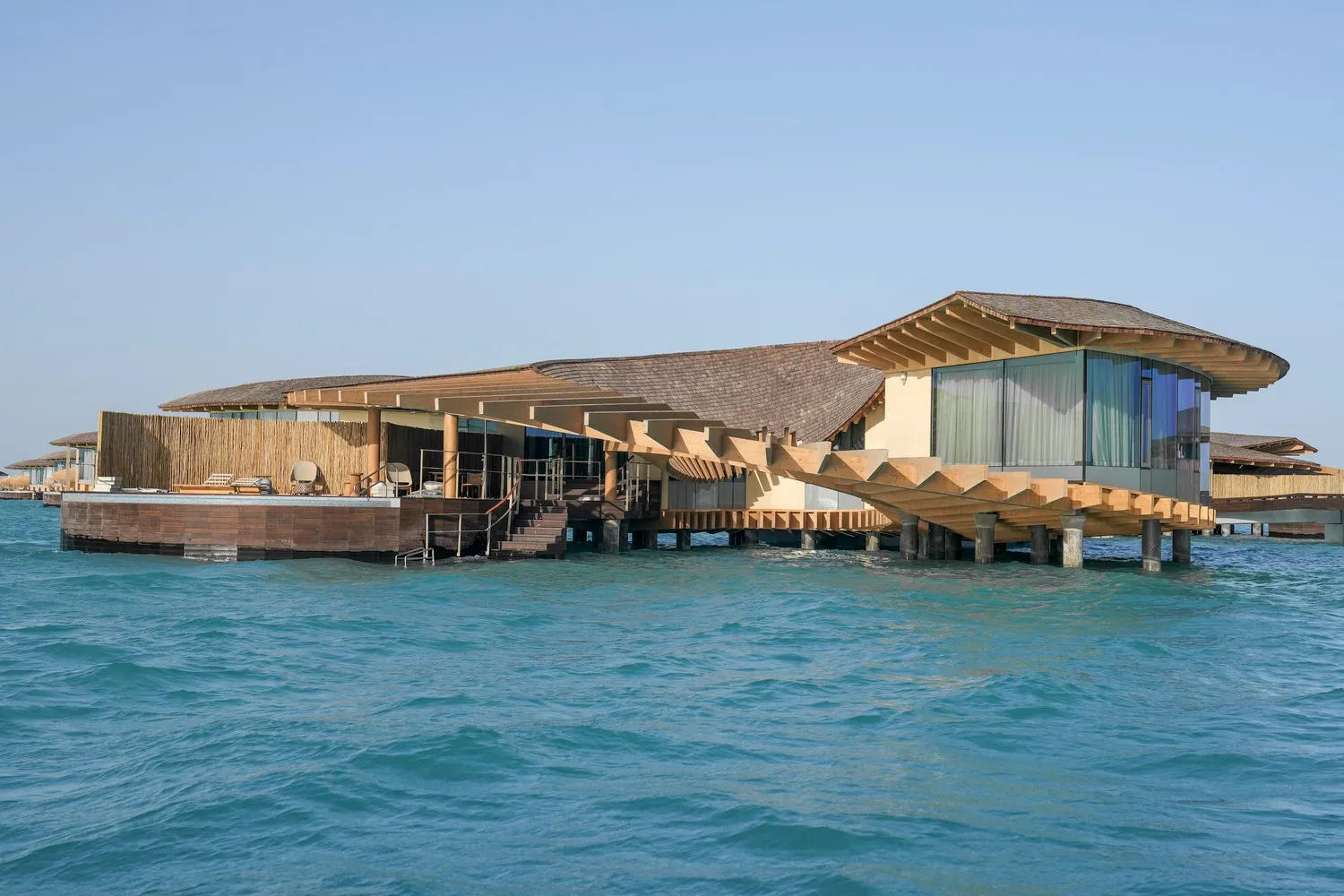 Modern, minimalist waterfront resort buildings floating on the ocean.