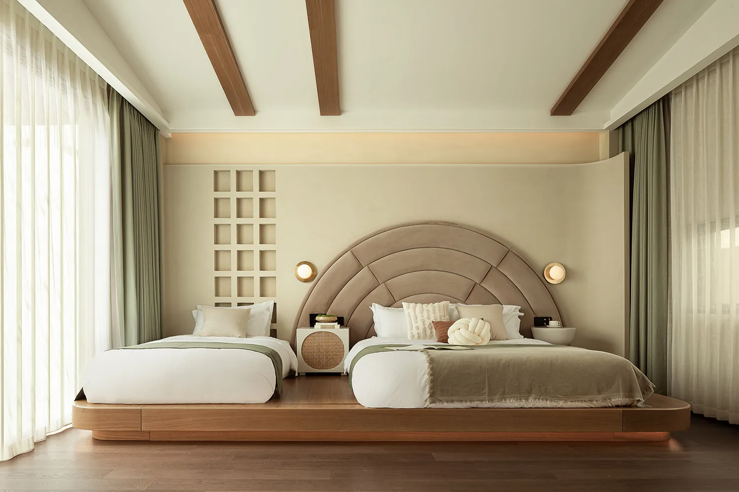 A modern bedroom featuring comfortable beds with soft lighting, a large window, and a rug with a wooden floor.