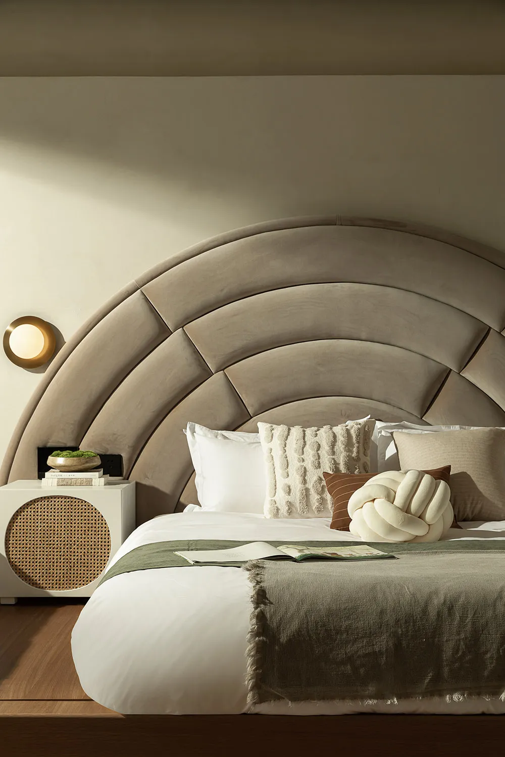 Modern minimalist bedroom with a textured beige headboard and wooden flooring.