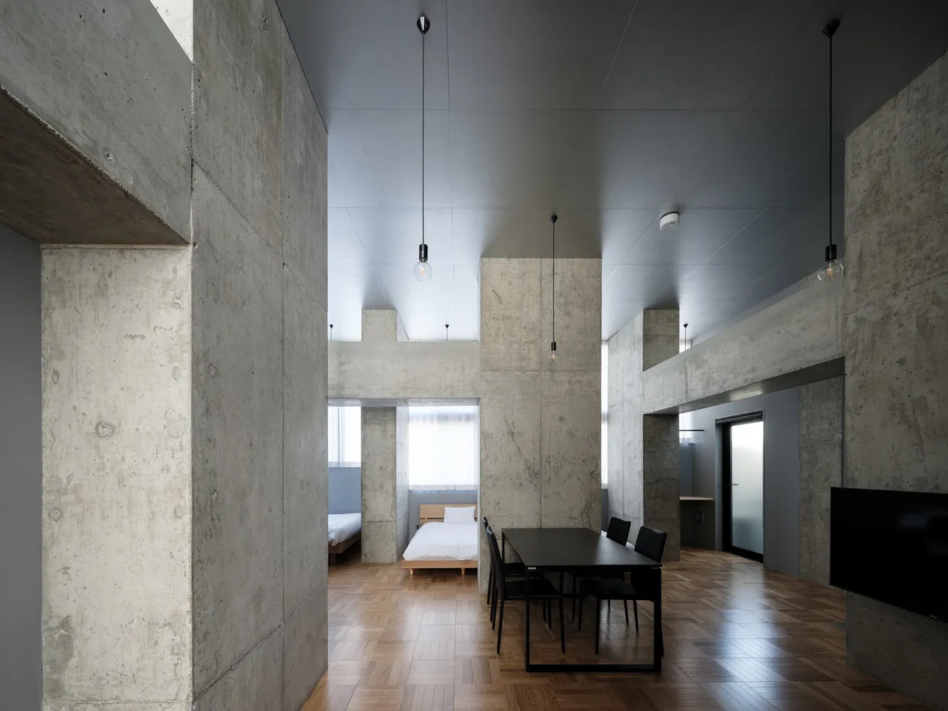 A photograph showcasing a modern industrial residential interior with concrete walls and wooden parquet flooring.