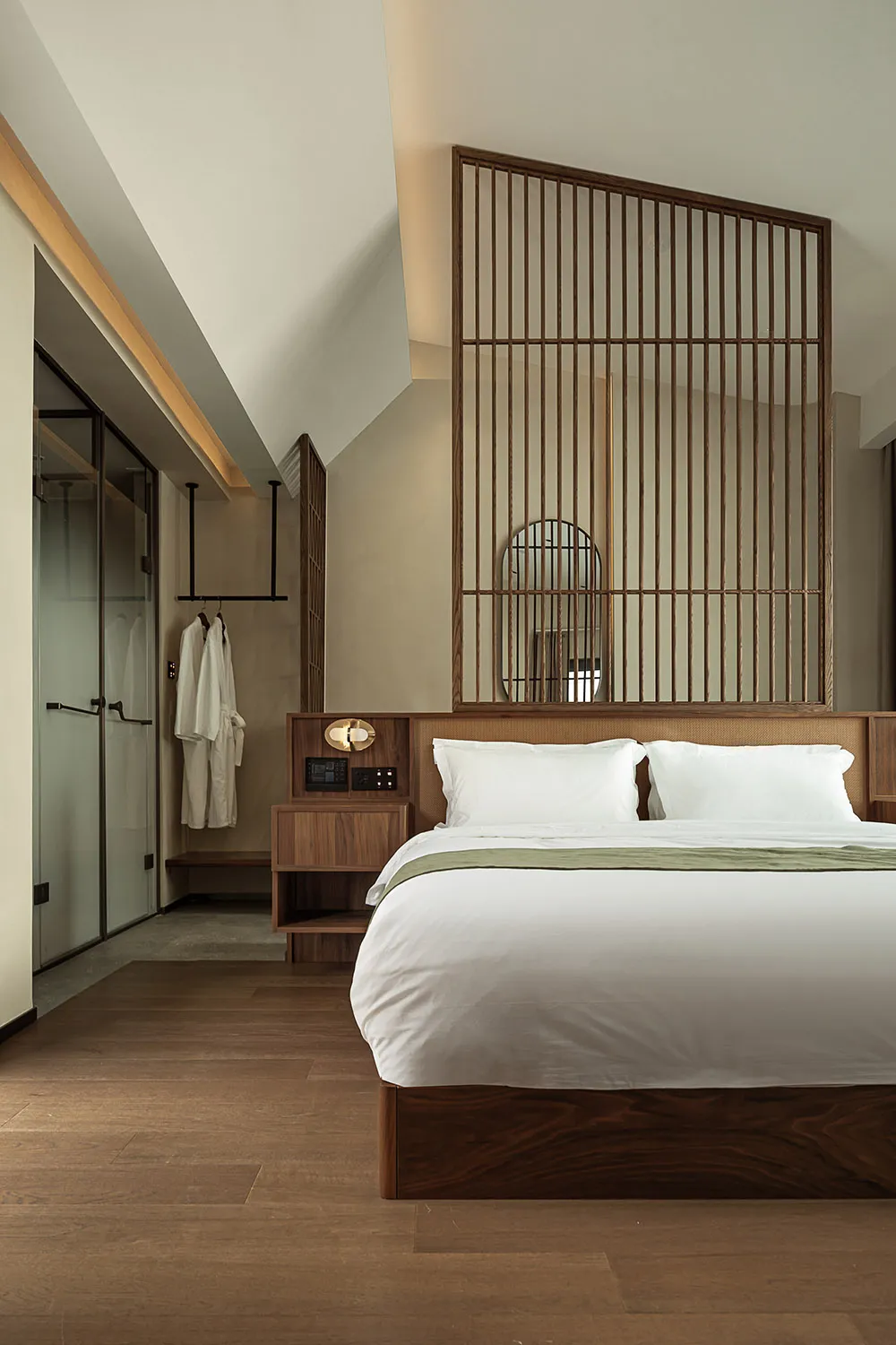 A minimalist bedroom featuring a wooden bed with white bedding and a bamboo partition.