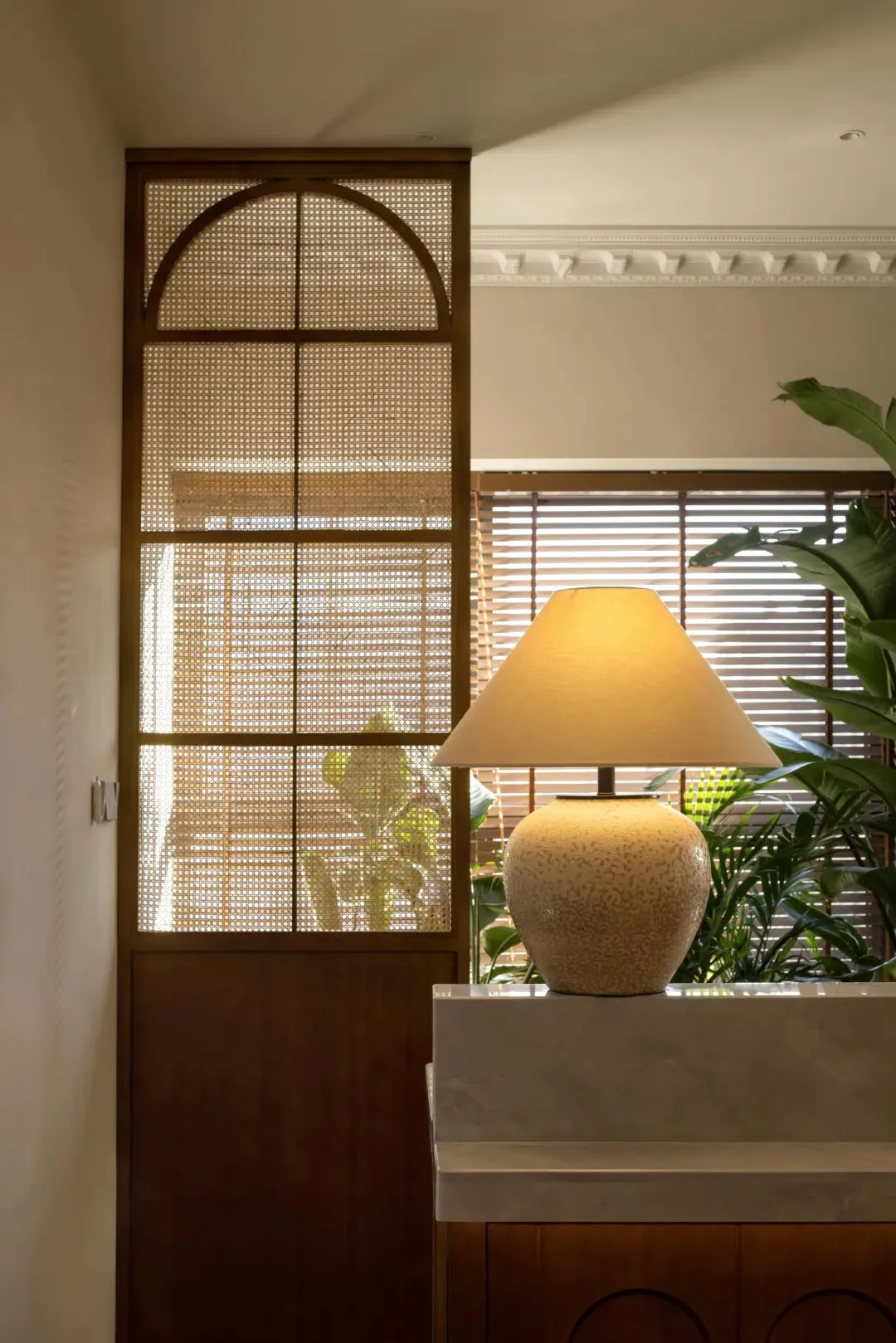 A ceramic lamp with a conical shade illuminates a space, adding a warm glow.