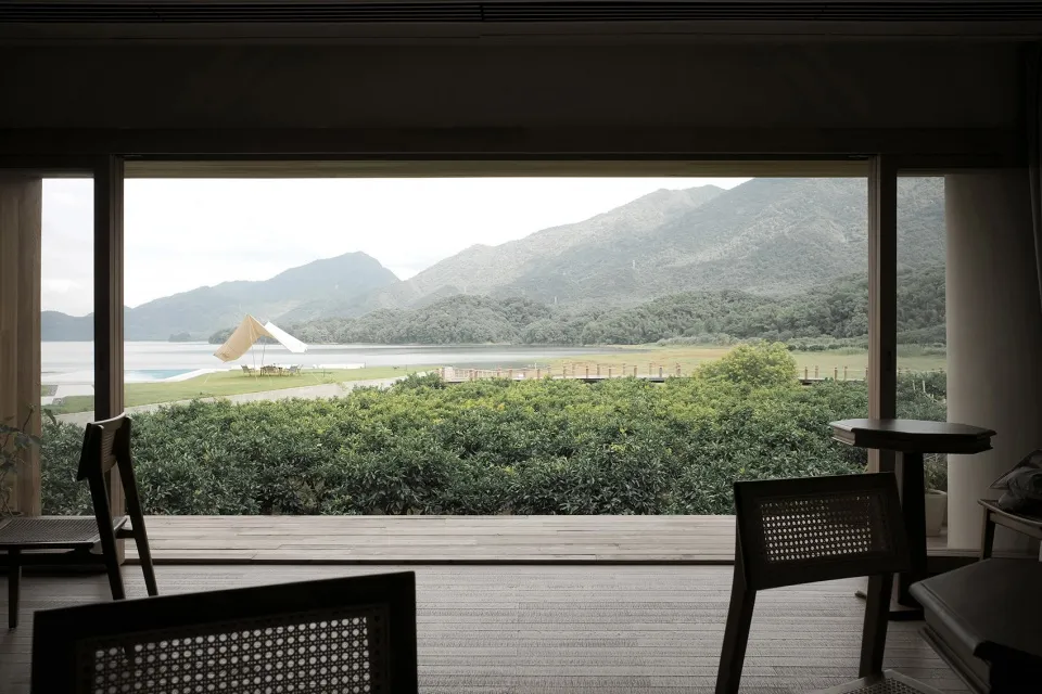 A minimalist interior design with a view of a living room through a large window overlooking a beautiful panorama of mountain
